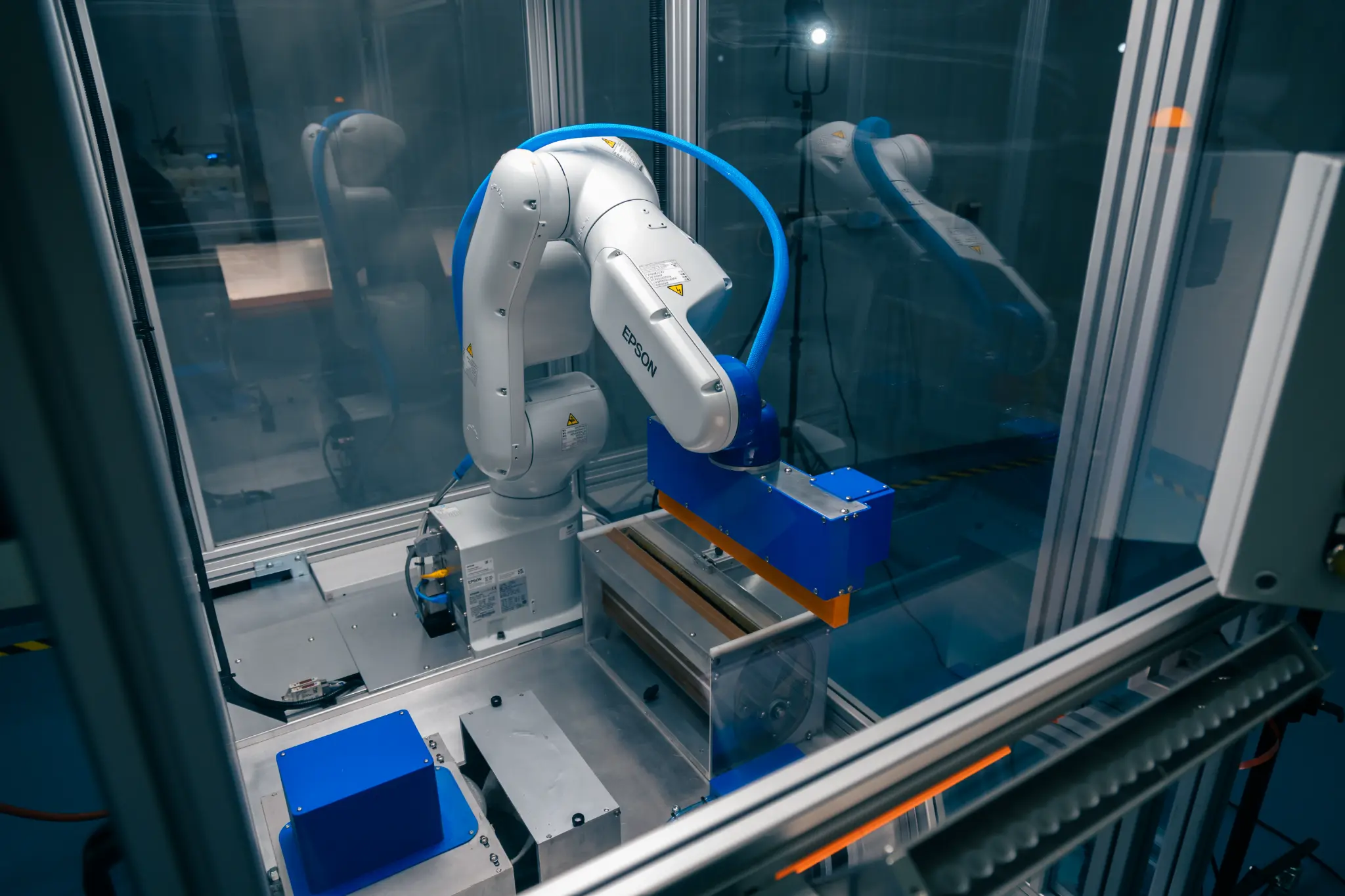Inside the Nu-Tec coating machine, showing its Epson robotic arm and purpose-built coating tooling